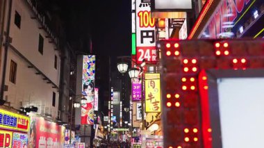 Tokyo, Japonya - 12 Nisan 2025: Shinjuku Şehri 'nin canlı yaşamını akşam saatlerinde yanan binalarla sokaklarda hareket eden insanlarla birlikte görmek. Çevirisi: 