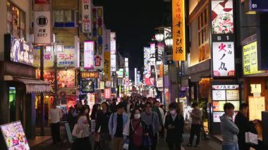 Tokyo, Japonya - 12 Nisan 2025: Shinjuku Şehri 'nin canlı yaşamını akşam saatlerinde yanan binalarla sokaklarda hareket eden insanlarla birlikte görmek. Çevirisi: 