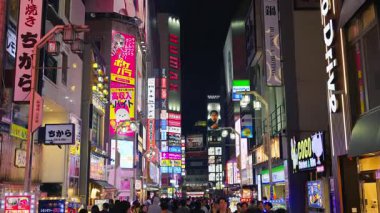 Tokyo, Japonya - 12 Nisan 2025: Shinjuku Şehri 'nin canlı yaşamını akşam saatlerinde yanan binalarla sokaklarda hareket eden insanlarla birlikte görmek. Çevirisi: 