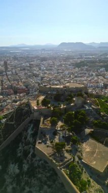 İspanya 'nın Alicante sahilindeki Santa Barbara Kalesi' nin arka planında şehir ve deniz olan insansız hava aracı görüntüsü. Dikey
