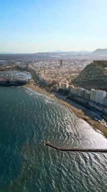 İspanya 'nın Alicante sahilindeki Santa Barbara Kalesi' nin arka planında şehir ve deniz olan insansız hava aracı görüntüsü. Dikey