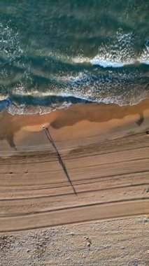 İspanya, Alicante 'de kıyıya vuran dalgalarla sahilde yürüyen adam. Dikey