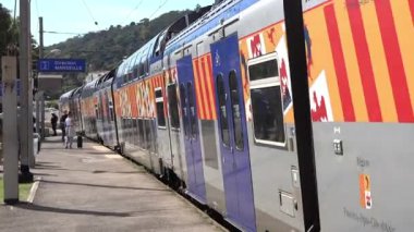 Cannes, Fransa - 2 Temmuz 2025: Bagajlı yolcular arka planda Marsilya yönünü gösteren bir işaretle bir istasyondan trene biniyorlar