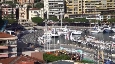 La Condamine, Monaco - 4 Temmuz 2025: Trafikli Quai Albert-1er kavşağı, Monako bayrakları, mevsimlik eğlence ve yerleşim yerlerinin altındaki Herkül Limanı 'na demirlemiş yatlar