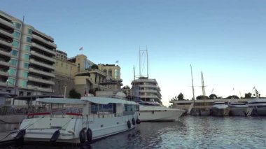 Monte Carlo, Monaco - 4 Temmuz 2025: Rıhtım boyunca lüks konutları bulunan modern katlı Yat Kulübü binasının yakınına kurulmuş yatlar ve lansmanlar