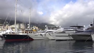 La Condamine, Monaco - 4 Temmuz 2025: Port Herkül 'e demirli lüks yatlar ve arka planda sisli tepeler