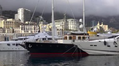 La Condamine, Monaco - 4 Temmuz 2025: Port Herkül 'e demirli lüks yatlar ve arka planda sisli tepeler