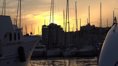 Yelkenli direkleri ve yatların siluetleri Cannes marinasında altın bir günbatımı gökyüzüne karşı