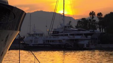 Yelkenli direkleri ve yatların siluetleri Cannes marinasında altın bir günbatımı gökyüzüne karşı