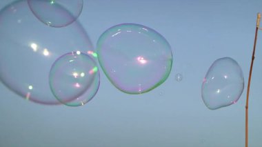 Bir sokak gösterisi sırasında mavi gökyüzünde yüzen renkli sabun köpükleri