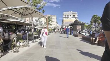 Cannes, Fransa - 10 Temmuz 2025: İnsanlar şehrin sokaklarında yürüyor, terasların yanında ve gün ışığında bir atlıkarınca