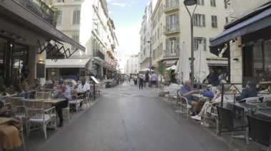 Cannes, Fransa - 10 Temmuz 2025: İnsanlar şehrin sokaklarında gün ışığında terasların yanında yürüyor