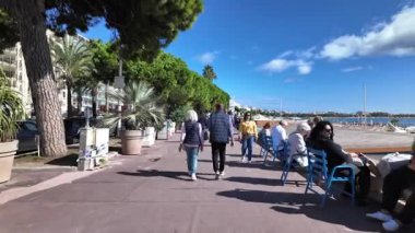 Cannes, Fransa - 12 Temmuz 2025: Güneşli bir günde insanlar deniz kenarında yürüyor