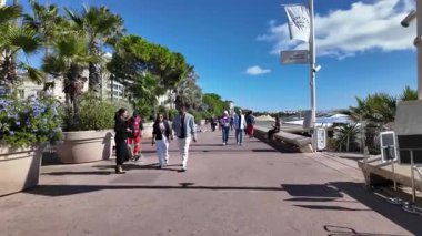 Cannes, Fransa - 12 Temmuz 2025: Güneşli bir günde insanlar deniz kenarında yürüyor