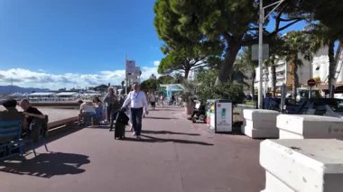 Cannes, Fransa - 12 Temmuz 2025: Güneşli bir günde insanlar deniz kenarında yürüyor