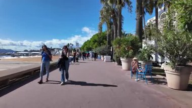 Cannes, Fransa - 12 Temmuz 2025: Güneşli bir günde insanlar deniz kenarında yürüyor