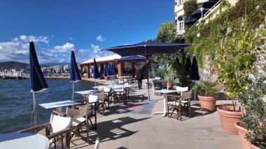 Cannes, Fransa - 12 Temmuz 2025: Mavi sulara bakan teras kapları, muz yaprakları ve şemsiyelerle kaplı huzurlu bir sahil yolu