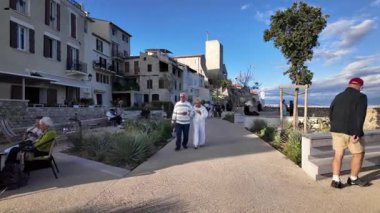 Antibes, Fransa - 14 Temmuz 2025: Sahildeki farklı binaların etrafında yürüyen insanların görüntüsü
