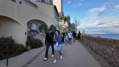 Antibes, Fransa - 14 Temmuz 2025: Sahildeki farklı binaların etrafında yürüyen insanların görüntüsü