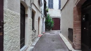 Antibes, Fransa - 14 Temmuz 2025: Bulutlu bir günde şehirdeki binalar arasındaki dar sokaklar