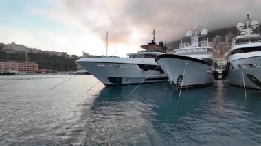 La Condamine, Monaco - 4 Temmuz 2025: Port Herkül 'e demirli lüks yatlar ve arka planda sisli tepeler