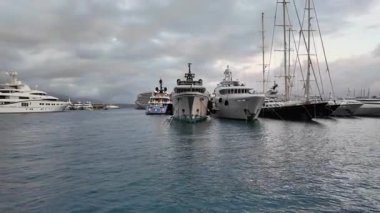La Condamine, Monaco - 4 Temmuz 2025: Port Herkül 'e demirli lüks yatlar ve arka planda sisli tepeler