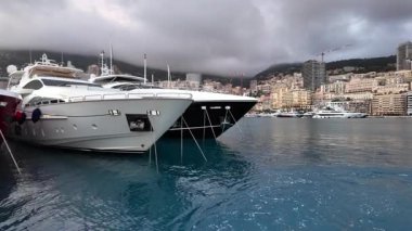 La Condamine, Monaco - 4 Temmuz 2025: Port Herkül 'e demirli lüks yatlar ve arka planda sisli tepeler