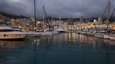 La Condamine, Monaco - 18 Temmuz 2025: Gri bulutlar altında yoğun yamaçlardaki dairelere karşı dolu yat limanı