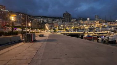 La Condamine, Monaco - 18 Temmuz 2025: Akşam limana bakan ve arka planda binalar bulunan bir gezinti alanı
