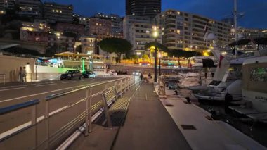 La Condamine, Monaco - 18 Temmuz 2025: Akşam limana bakan ve arka planda binalar bulunan bir gezinti alanı