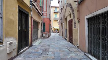 Villefranche-sur-Mer, Fransa - 18 Temmuz 2025: Pastel binalar arasında gün ışığında dar bir sokakta yürüyüş
