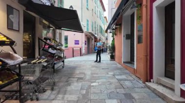 Villefranche-sur-Mer, Fransa - 18 Temmuz 2025: Pastel binalar arasında gün ışığında dar bir sokakta yürüyüş