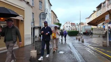 Antibes, Fransa - 20 Temmuz 2025: İnsanlar yağmur altında şehrin sokaklarında yürüyor