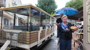 Antibes, Fransa - 20 Temmuz 2025: İnsanlar yağmur altında şehrin sokaklarında yürüyor