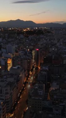 Akşam İspanya 'nın Alicante kentindeki binalar arasında hareket eden arabaların hava aracı görüntüsü. Dikey