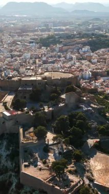 İspanya 'nın Alicante kıyısındaki Santa Barbara Kalesi' nin arka planında şehir olan insansız hava aracı görüntüsü. Dikey