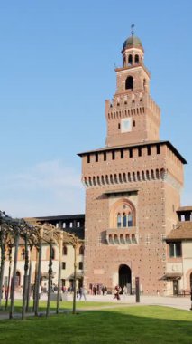 Milan, İtalya - 20 Mart 2025 Sforzesco Kalesi 'nde gündüz vakti Filarete Kulesi yakınlarında yürüyen insanlar. Dikey