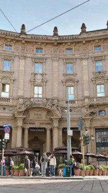 Milan, İtalya - 21 Mart 2025: Palazzo Broggi 'nin önünden geçen insanlar ve arabalar. Dikey