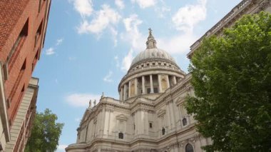 St. Paul Katedrali 'nin Kubbesi ağaçların üzerinden yükseliyor. Arkasında Londra, İngiltere' de açık mavi bir gökyüzü var.