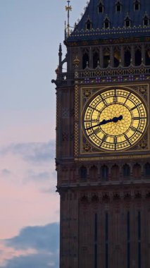 Big Ben 'in yakın çekim görüntüsü Londra, İngiltere' de alacakaranlıkta aydınlandı. Dikey