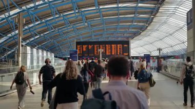 Londra, İngiltere - 14 Mayıs 2025: Waterloo İstasyonu 'nun güneşli iç kesimindeki ikonik kalkış tahtası altında yürüyen banliyö sakinleri
