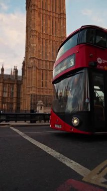 Londra, İngiltere - 11 Mayıs 2025: akşam Big Ben yakınlarında hareket eden kırmızı çift katlı bir güverteye yaklaş. Dikey
