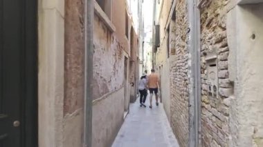 Venedik, İtalya - 9 Temmuz 2025: İnsanlar şehrin dar sokaklarında binaların arasında yürüyor