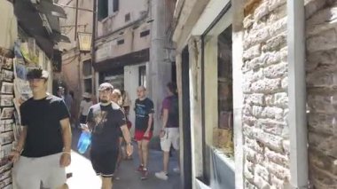 Venedik, İtalya - 9 Temmuz 2025: İnsanlar şehrin dar sokaklarında binaların arasında yürüyor