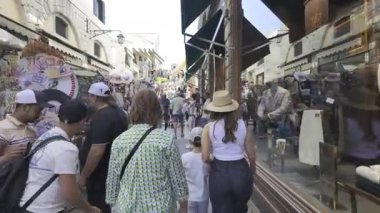 Venedik, İtalya - 9 Temmuz 2025: Turistler şehrin dar sokaklarında gün ışığında farklı butiklerin yanında yürüyorlar
