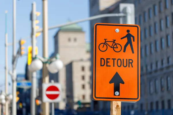 Orange detour sign for bikes and pedestrians. Closed way for bikes and walking people in downtown Ottawa, Canada