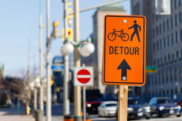 Orange detour sign for bikes and pedestrians. Closed way for bikes and walking people in downtown Ottawa, Canada