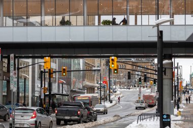 Ottawa, Canada - January 23, 2023: Rideau street with public bus stop, people walking on sidewalk and cars on road in downtown of the city