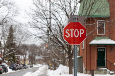 Stop sign in a residential neighborhood at crossroads in winter. Cars parking along the street