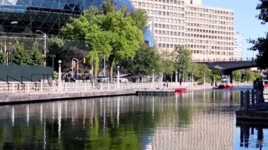 Ottawa, Kanada - 19 Eylül 2021: Rideau Kanalı, güneşli bir yaz gününde Ottawa şehir merkezindeki toprak setinde yürüyen insanlarla dolu.
